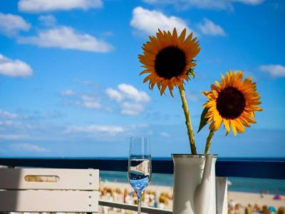 Tisch auf Balkon mit Sonnenblumen und Meerblick